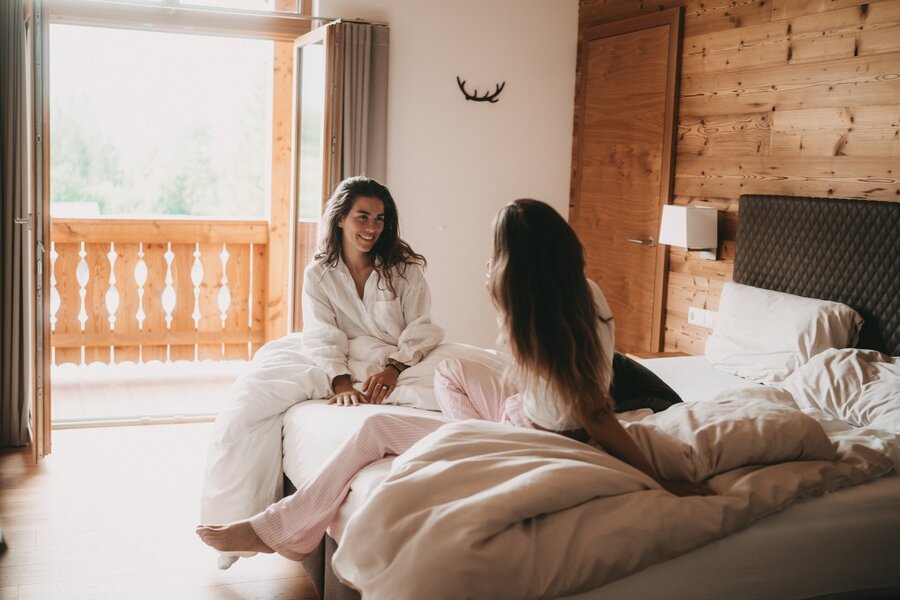 Two women chatting on a bed in a cozy bedroom