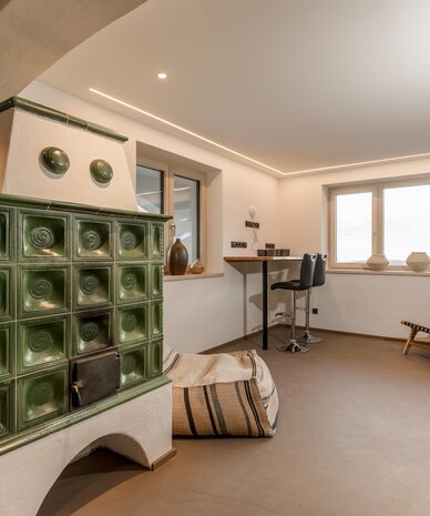Green tiled stove in a modern living space with seating