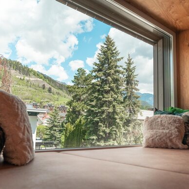 Cozy window seat indoors with mountains and trees outside.