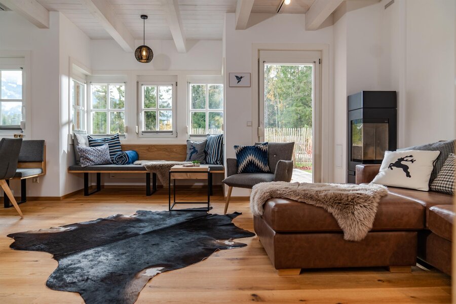 Bright living room with wooden beams, gray seating, and a fireplace.