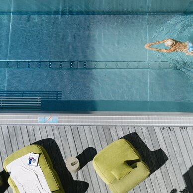 Aerial view of swimming pool with swimmer and deck chairs.