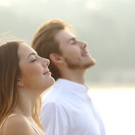 Ein Mann und eine Frau draußen mit geschlossenen Augen, Sonnenlicht genießen