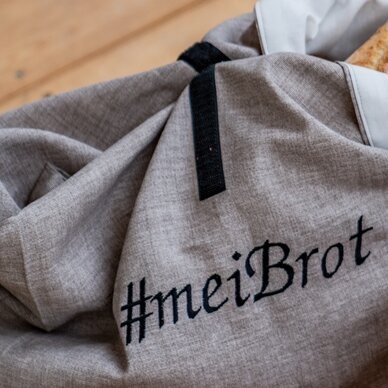 Graue Stofftasche mit schwarzem Henkel und Brot sichtbar