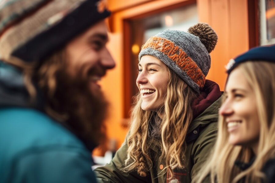 Drei Freunde in Winterkleidung lachen draußen zusammen.
