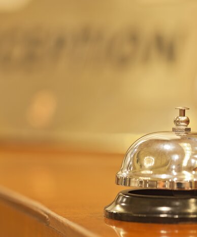 Glänzende Metall-Glocke auf Holztresen im Empfangsbereich