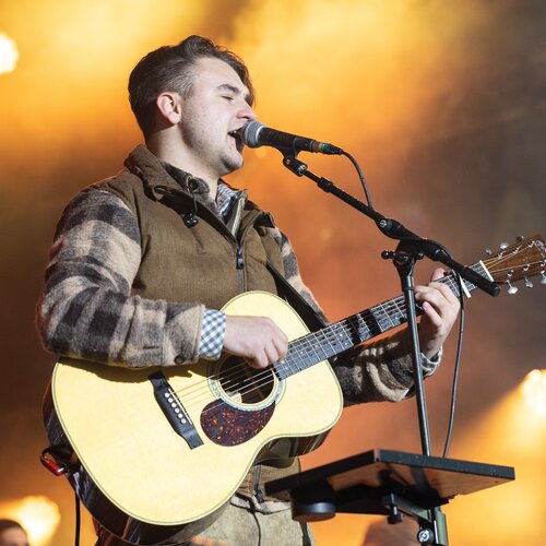 Male musician with acoustic guitar performing on stage | © Harald Steiner