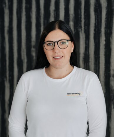 Portrait of a woman with glasses in a white shirt.