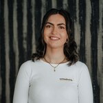 Smiling young woman wearing white long-sleeve shirt with small logo on chest