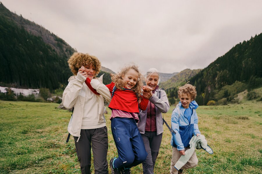 Family of four hiking outdoors, jumping for joy