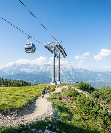 Seilbahngondel über Berglandschaft mit Radfahrern | © Christoph Oberschneider