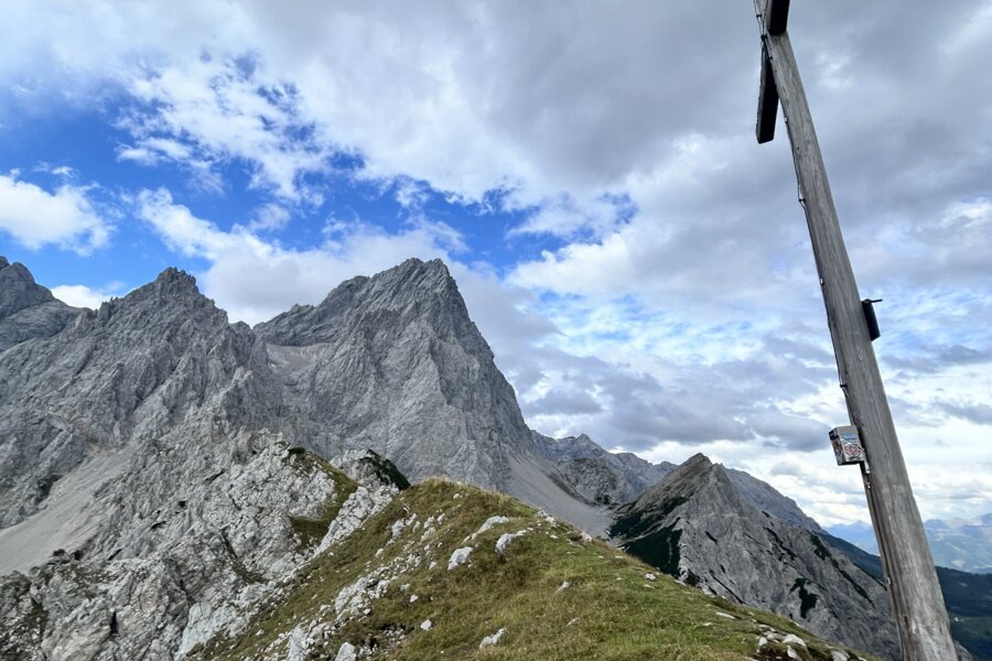 Rauer Bergkamm mit schroffen Gipfeln und einem hohen Holzkreuz.