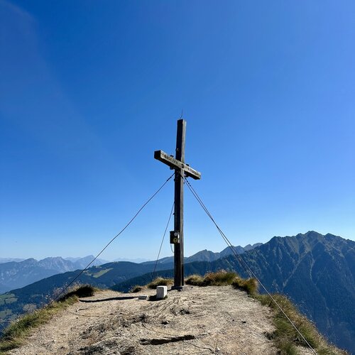 Wooden cross on mountain summit with cables