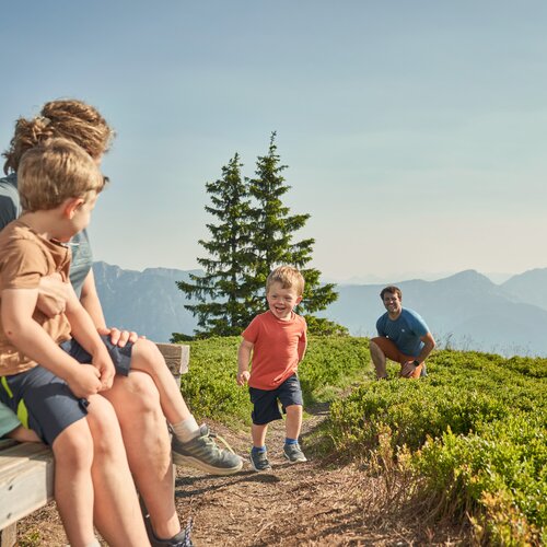 Familie sitzt auf Bank am Bergpfad mit Alpenblick | © Peter Burgstaller