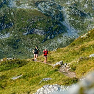 Zwei Wanderer wandern auf einem schmalen Bergpfad.