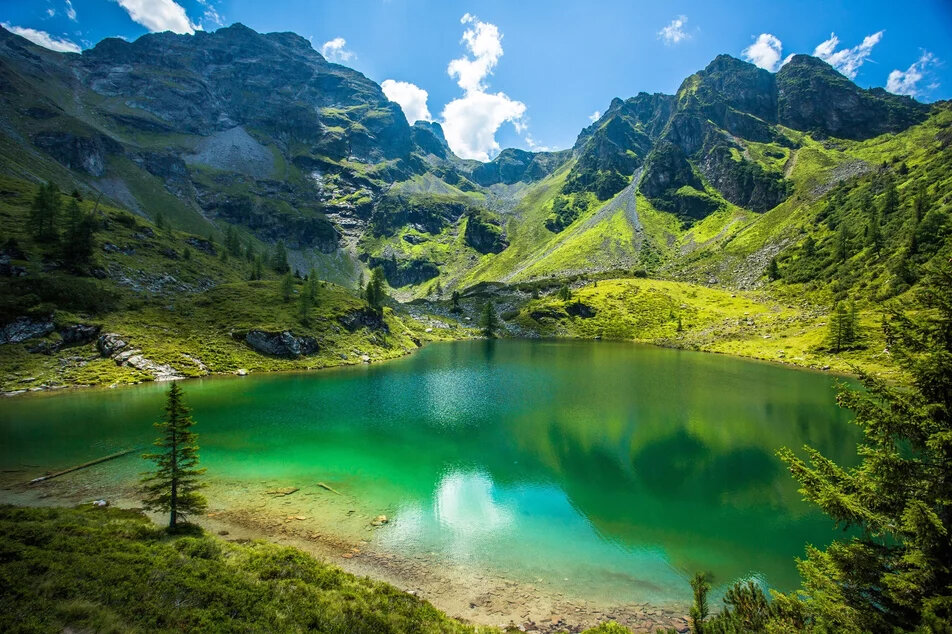 Smaragdgrüner Bergsee in alpiner Tallandschaft