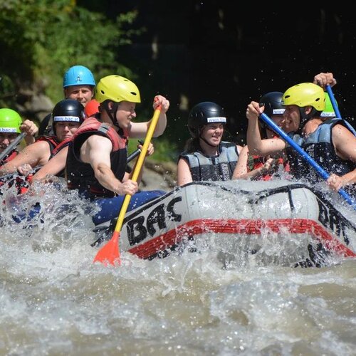Gruppe von Menschen beim Wildwasser-Rafting in einem Raftingboot