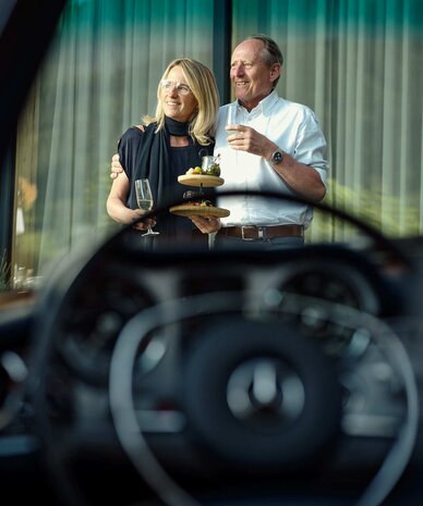 Lächelndes Paar im Freien, hält Weingläser und Snacks | © RaphaelGabauer