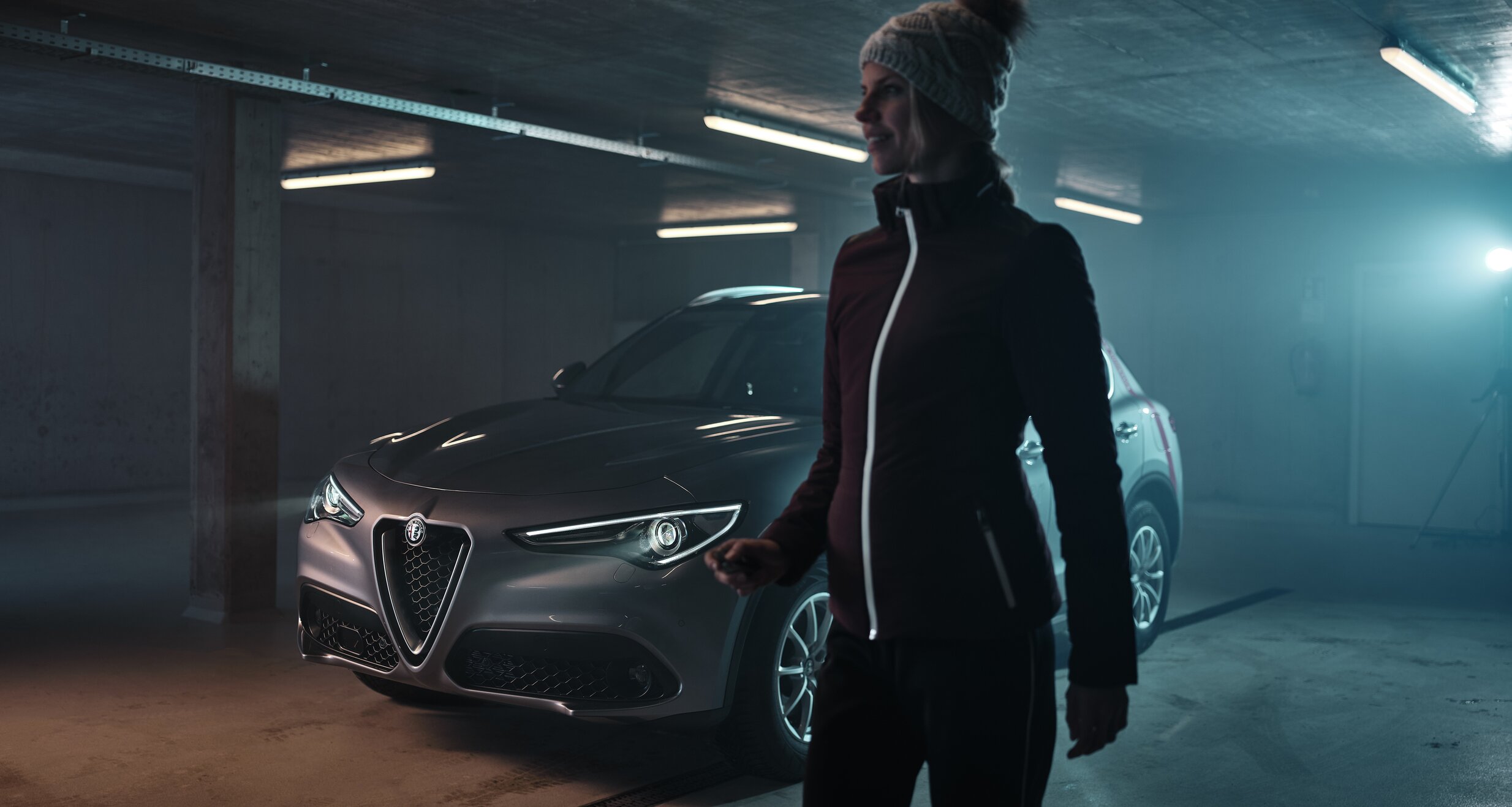 Person mit Mütze neben einem silbernen Auto in einer Parkgarage | © RAPHAELGABAUER.COM