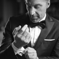 Mann im Smoking richtet Manschettenknopf am Hemd | © RAPHAELGABAUER.COM