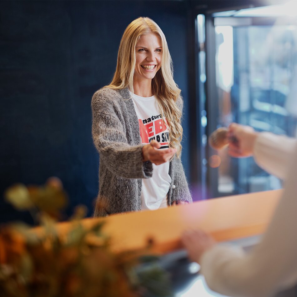 Lächelnde Frau am Empfang reicht einem Kunden die Hand