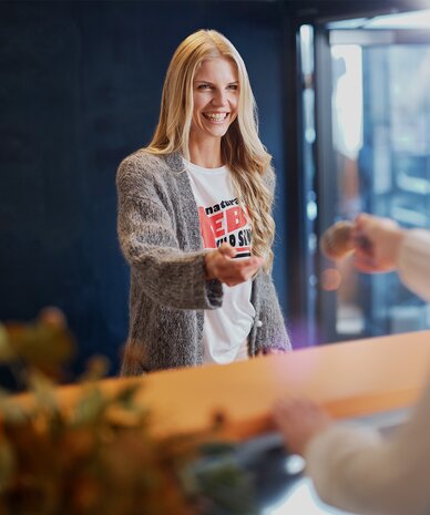 Smiling woman at reception extending hand to customer