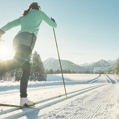 Skifahrer von hinten in grüner Jacke gleitet durch verschneite Landschaft | © Peter Burgstaller