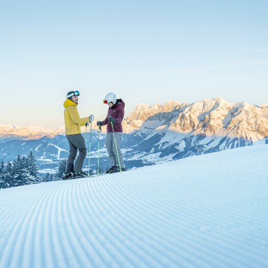 Zwei Skifahrer unterhalten sich auf verschneiter Piste mit Berglandschaft | © Peter Burgstaller