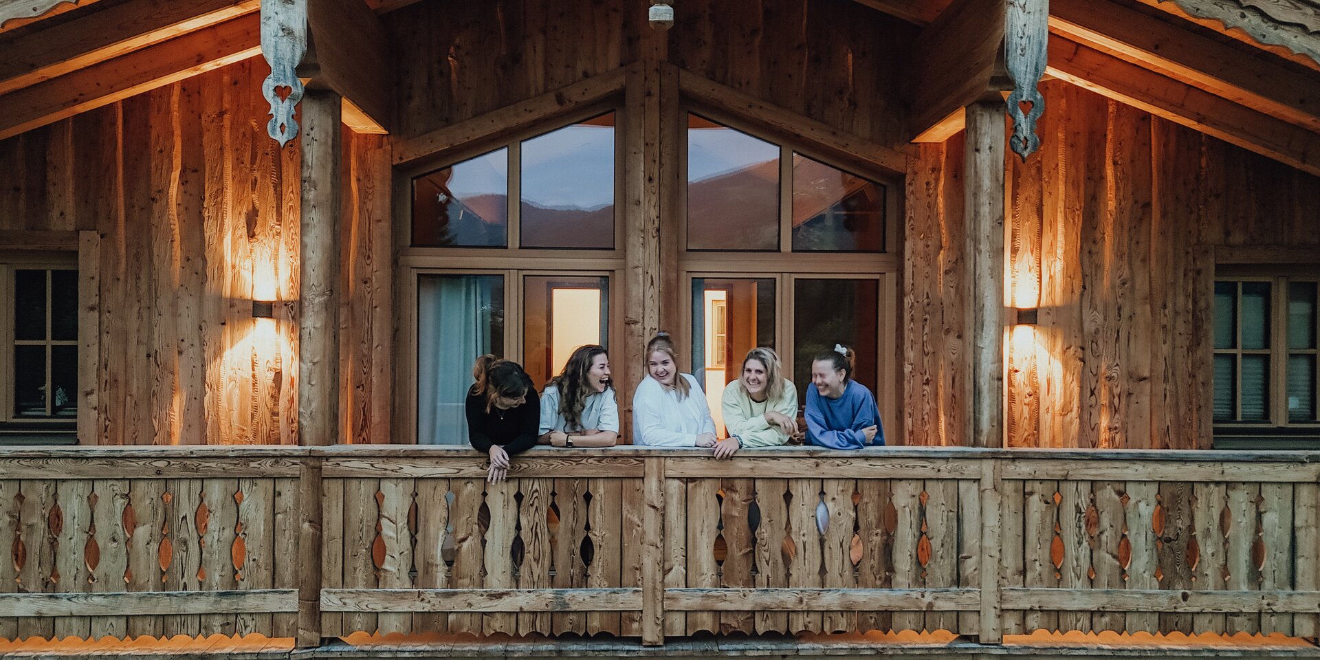 Fünf Freunde lehnen sich am Holzbalkon eines Blockhauses
