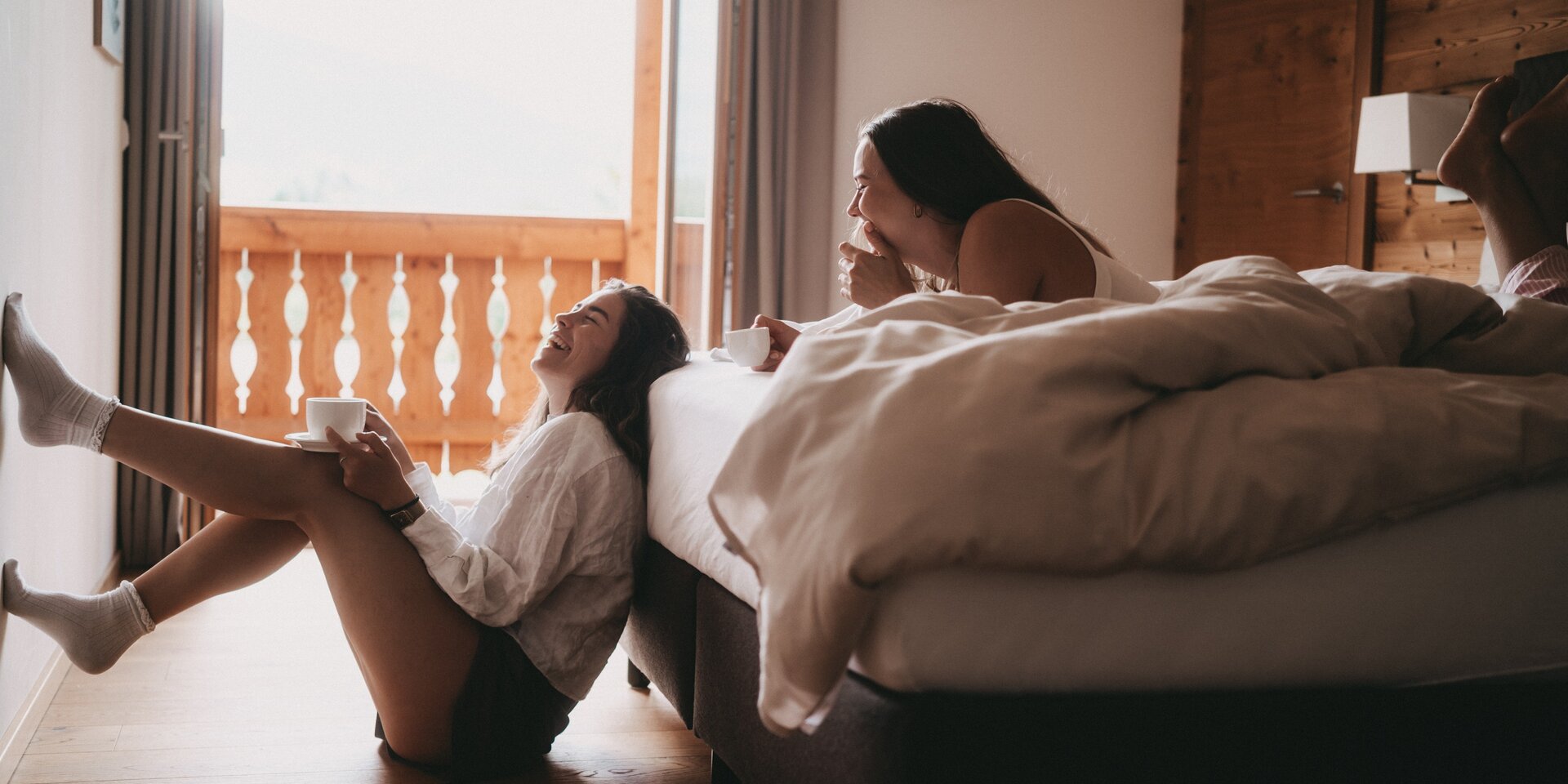 Zwei Frauen lachen, Kaffee trinken im Schlafzimmer