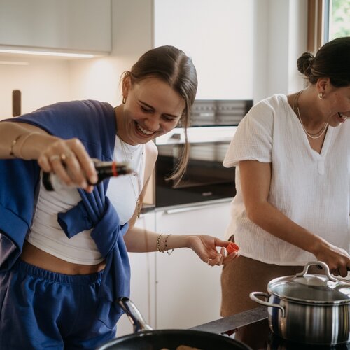 Zwei Freundinnen kochen zusammen in einer hellen Küche