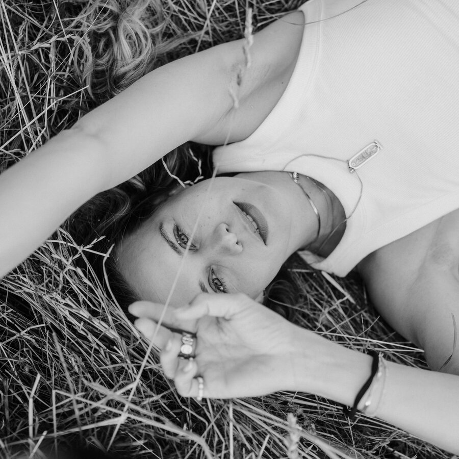 Frau liegt im Gras und blickt zur Kamera.