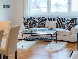 Wohnzimmer mit beigem Sofa und gestreiften sowie floralen Kissen