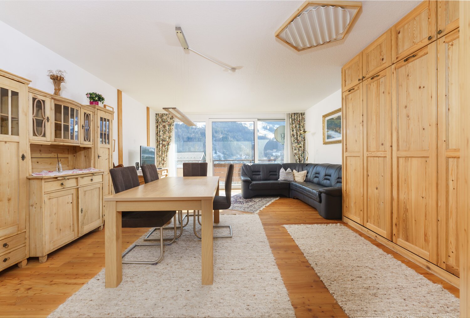 Wohnzimmer mit Holzmöbeln, Esstisch und Ledersofa