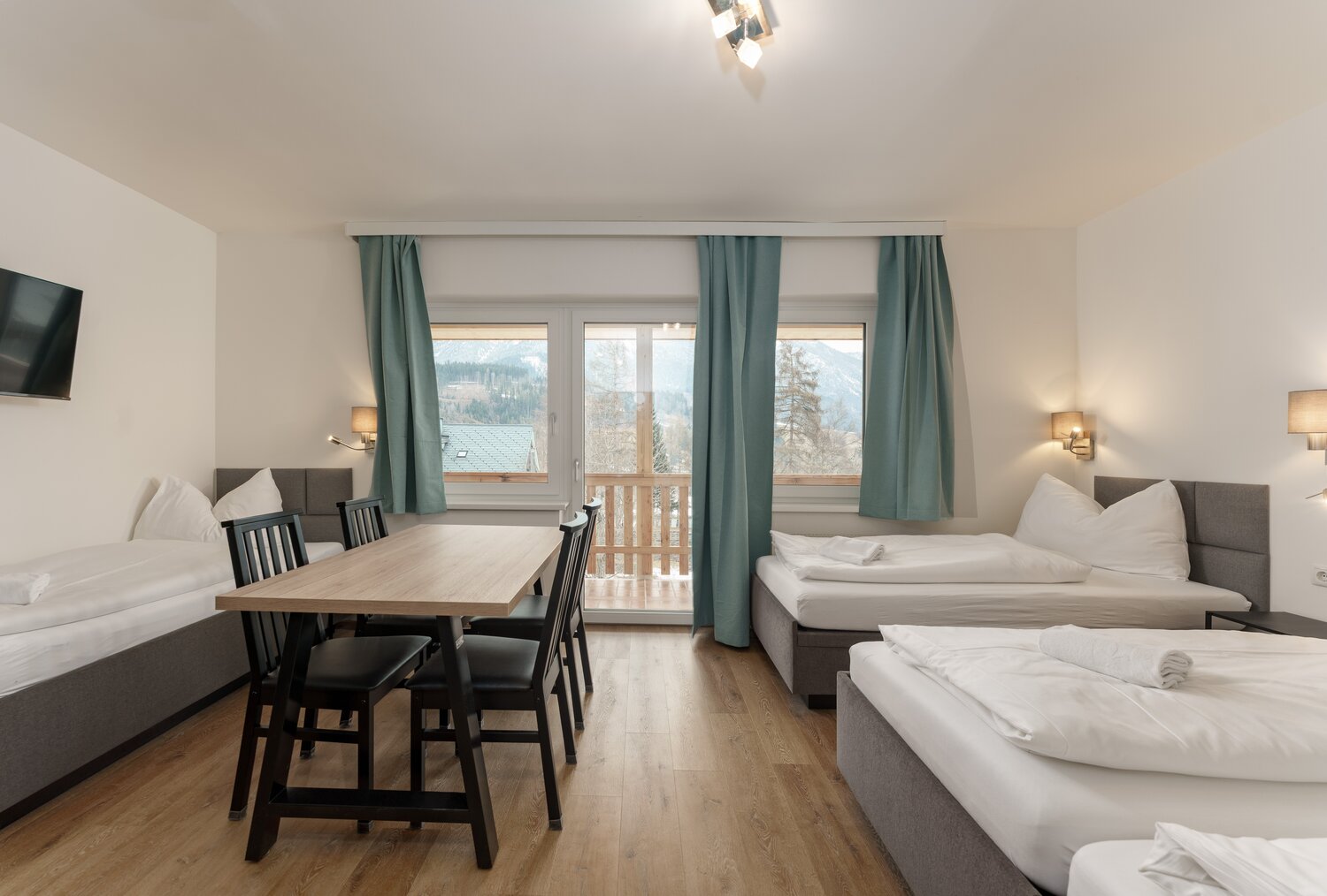 Hotelzimmer mit zwei Betten, Tisch und Balkonblick