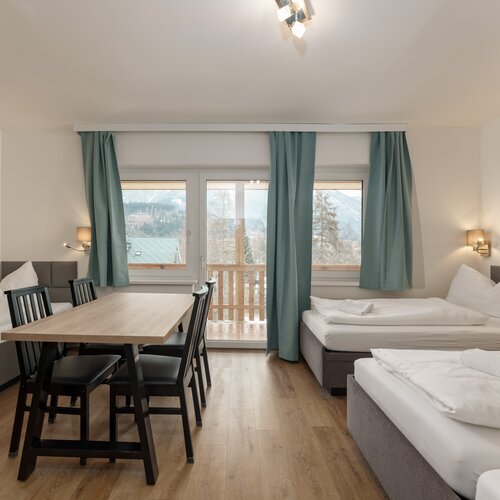 Hotelzimmer mit zwei Betten, Tisch und Balkonblick