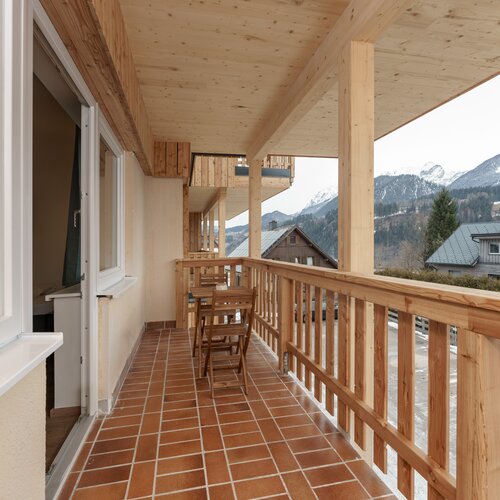 Holzbalkon mit Tisch und Stühlen, Bergblick