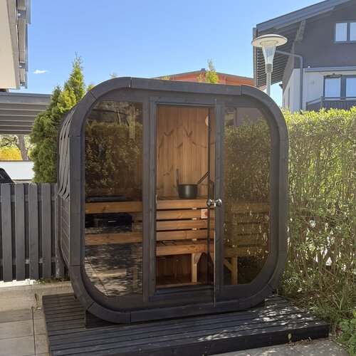 Outdoor glass-walled sauna cabin with wooden benches
