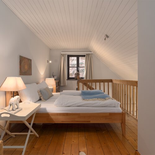 Cozy attic bedroom with slanted white ceiling panels