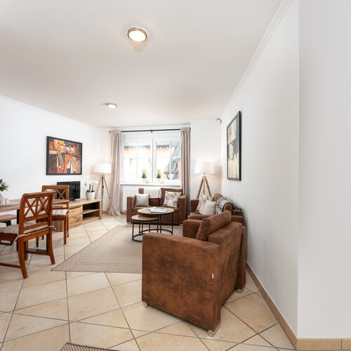 Wohnzimmer mit braunen Sofas, Couchtisch und Kunstwerken