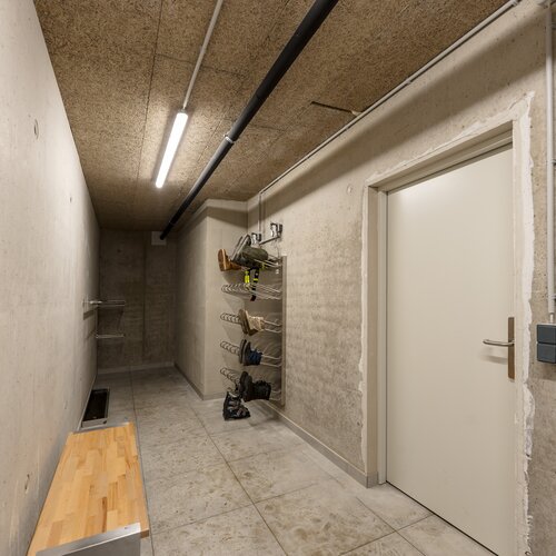 Industrial concrete hallway with shoe rack and bench