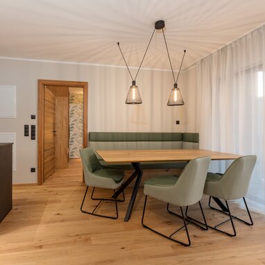 Modern dining area with wooden table and green upholstered chairs