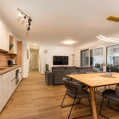 Open-plan kitchen, dining table, and living area with large windows