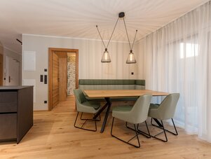 Dining area with wooden table, green chairs, and pendant lights