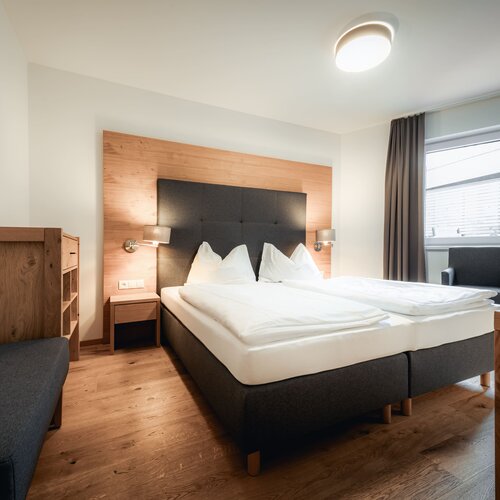 Hotelzimmer mit großem Bett und Holz-Kopfteil