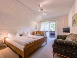 Helles Hotelzimmer mit großem Bett, Sitzecke und Balkonzugang