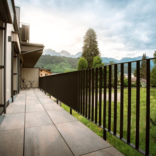 Modern balcony with tiled floor and metal railing overlooking mountains