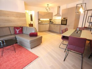 Open-plan living room with gray sofa and red accents.