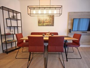 Dining room with wooden table, red upholstered chairs, and modern lighting