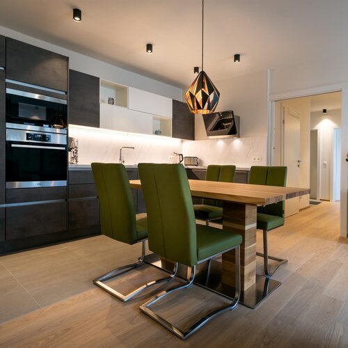Modern kitchen with dark cabinets and green upholstered chairs