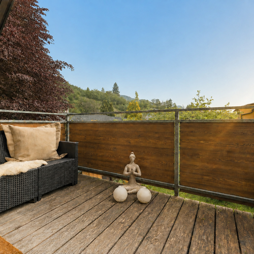 Balcony seating area on wooden deck with meditation statue and hills